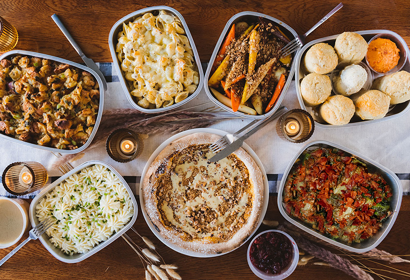 A Thanksgiving spread in to-go trays on a wooden table